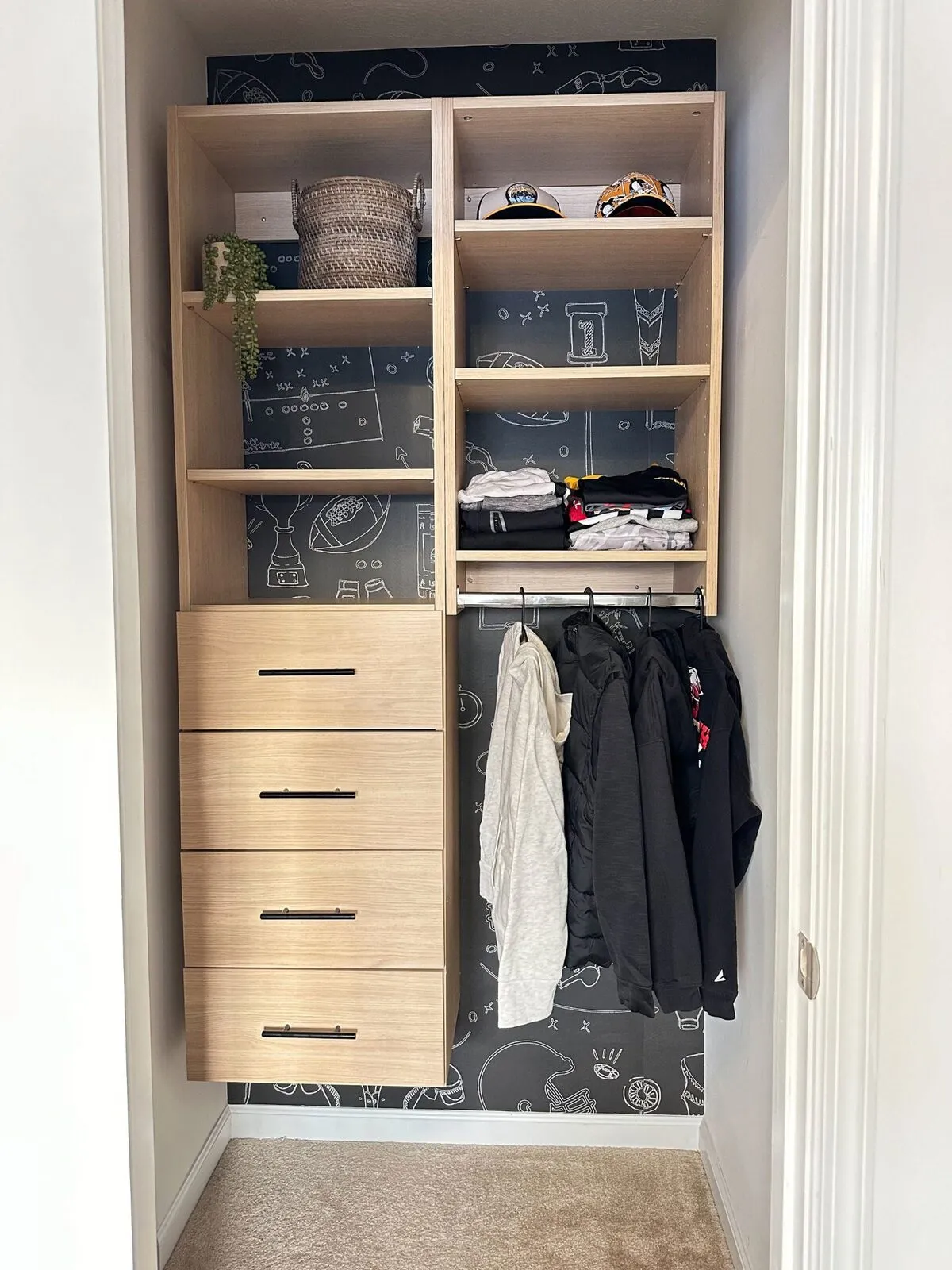 Kids reach-in closet with oak drawers and sports themed wallpaper