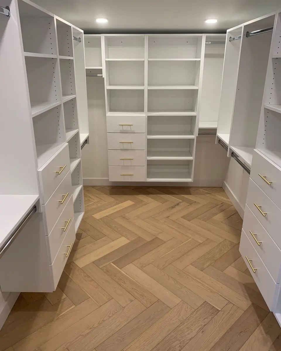 Walk-in closet with gold hardware and herringbone floors