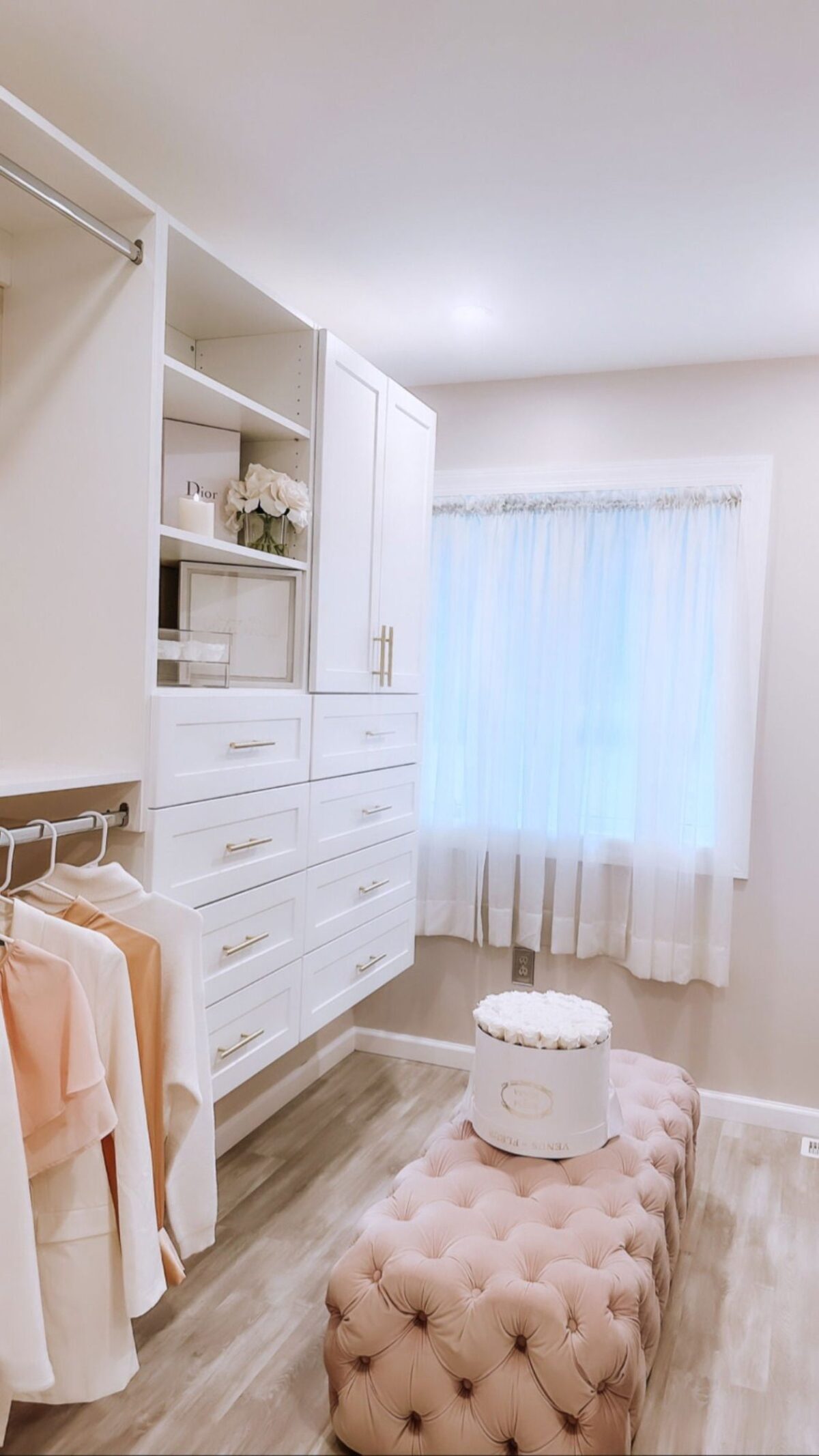 Luxury white dressing room with gold hardware and tufted ottoman