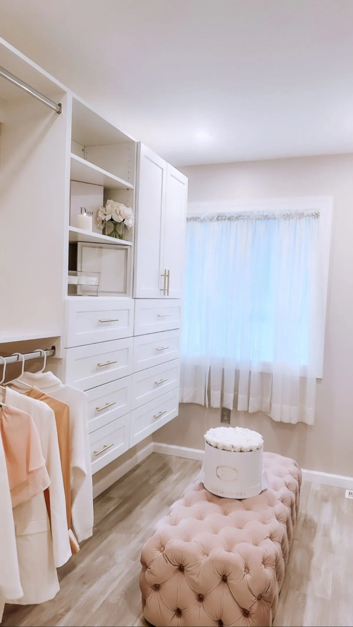 Luxury white dressing room with gold hardware and tufted ottoman