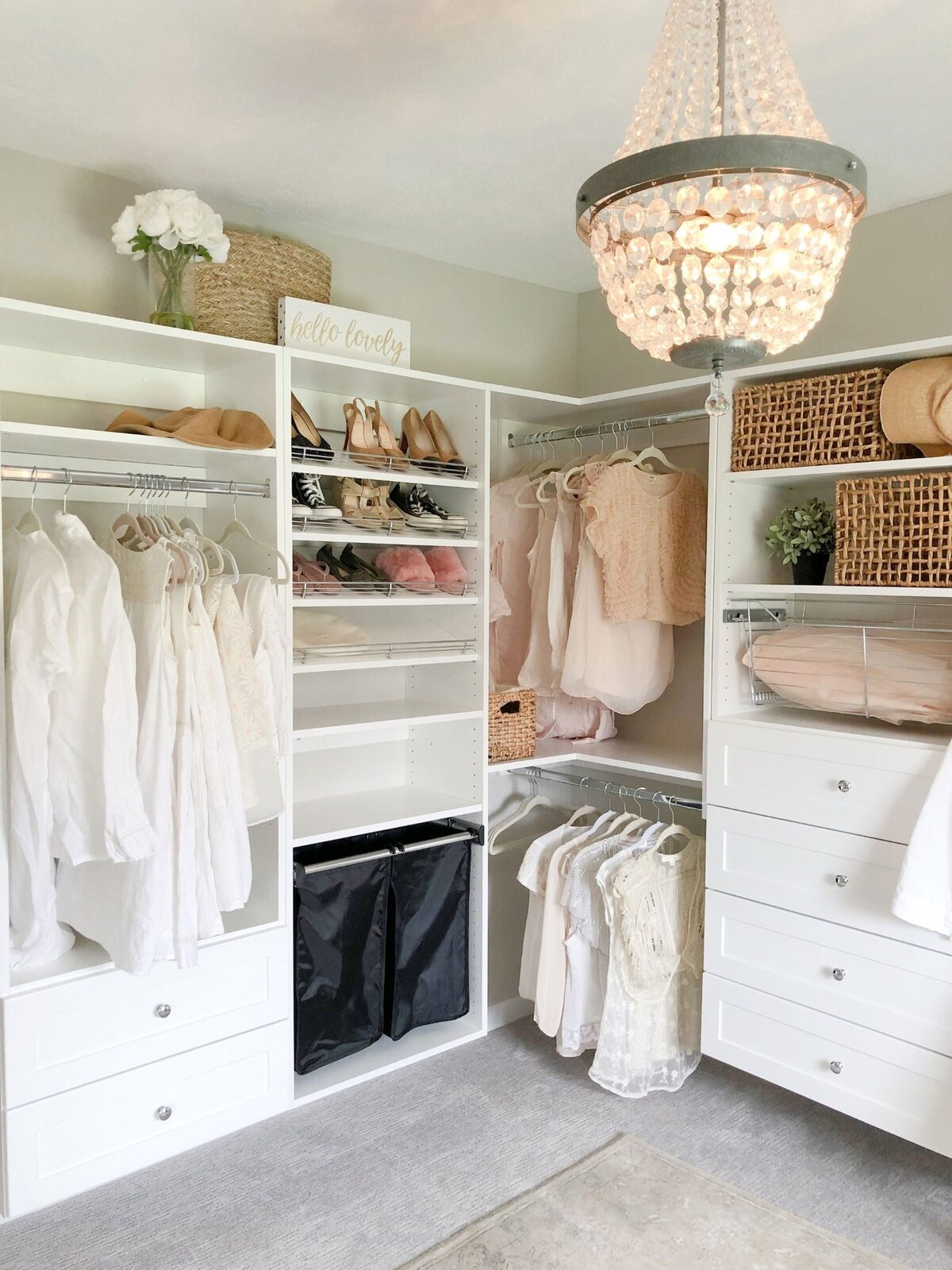 White walk-in closet with angled shoe racks chandelier and built-in hamper