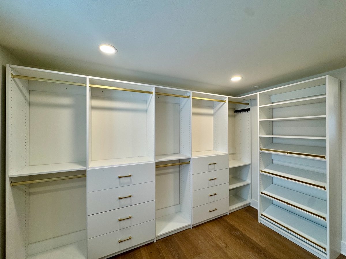 Custom walk-in closet with shoe storage and brass hardware installed in a Madison, WI home