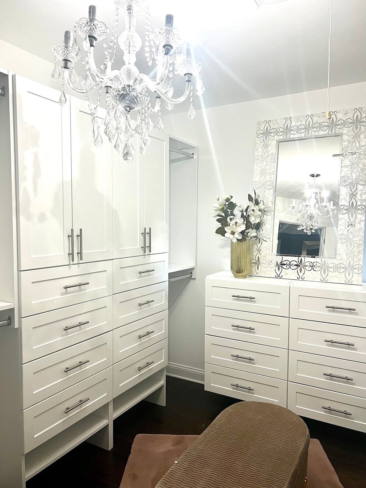 White walk-in closet with chandelier and drawers